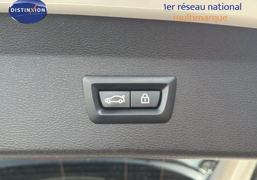 Boutons d'ouverture et de verrouillage de hayon sur la garniture intérieure blanche d'un BMW X1 2022 vue en gros plan.
