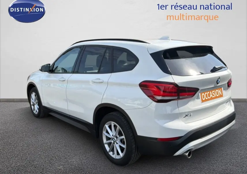 BMW X1 blanc vu en 3/4 arrière droit, mettant en valeur ses feux arrière et sa silhouette compacte SUV.