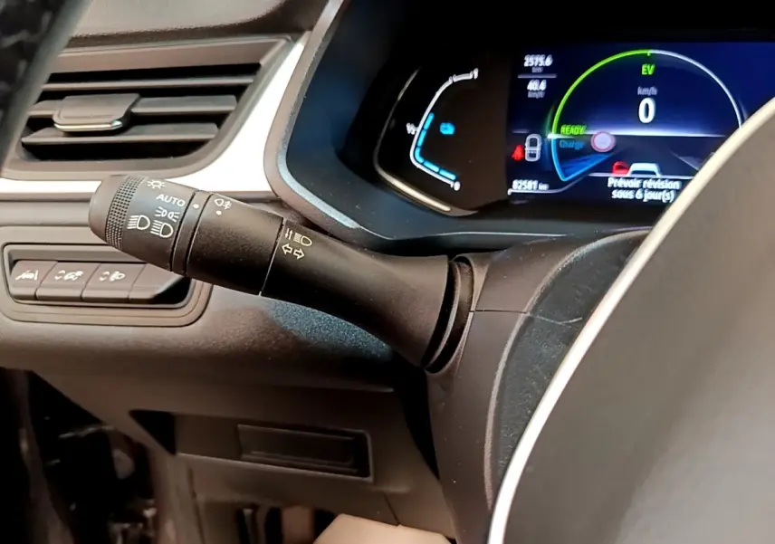 Gros plan sur la commande des phares et clignotants à gauche du volant du Renault Captur gris foncé, tableau de bord numérique visible.