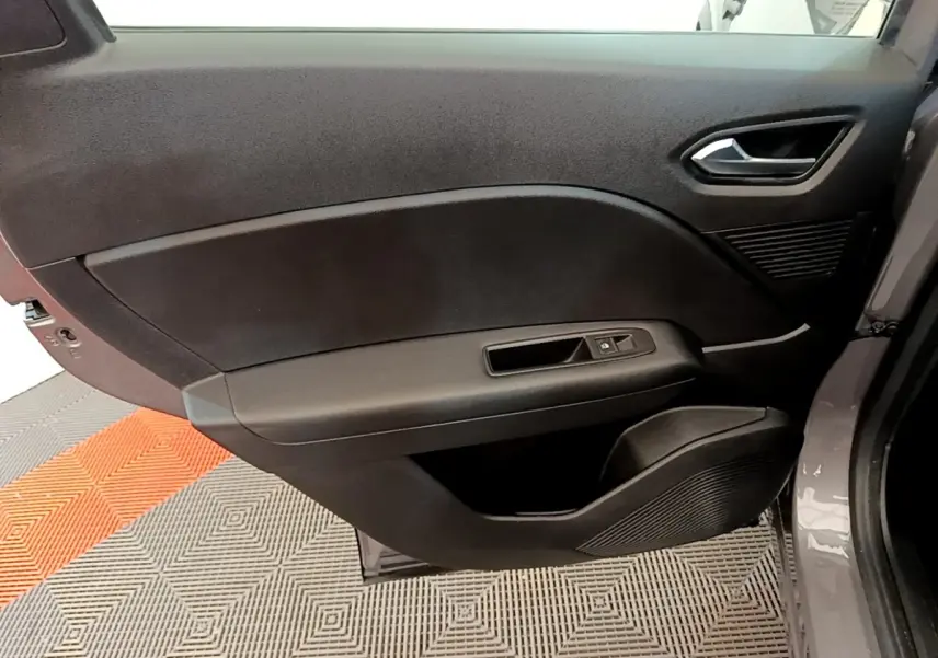 Vue rapprochée de la porte avant droite du Renault Captur gris foncé, montrant la poignée et les commandes de fenêtre.