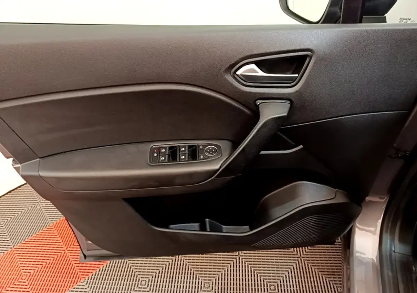 Gros plan sur la porte avant gauche gris foncé du Renault Captur Zen E-Tech hybride 2022 avec commandes de vitres et poignée intégrée.