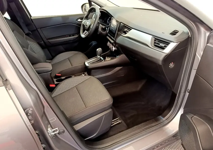 Intérieur avant droit du Renault Captur Zen E-Tech gris foncé, montrant sièges tissu et tableau de bord avec écran tactile.