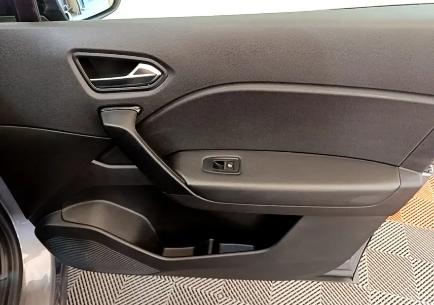 Vue rapprochée de la porte intérieure côté droit du Renault Captur gris foncé, montrant la poignée et le bouton de verrouillage.