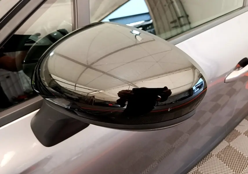 Gros plan sur le rétroviseur droit noir brillant du Renault Captur gris foncé, avec reflet intérieur visible.