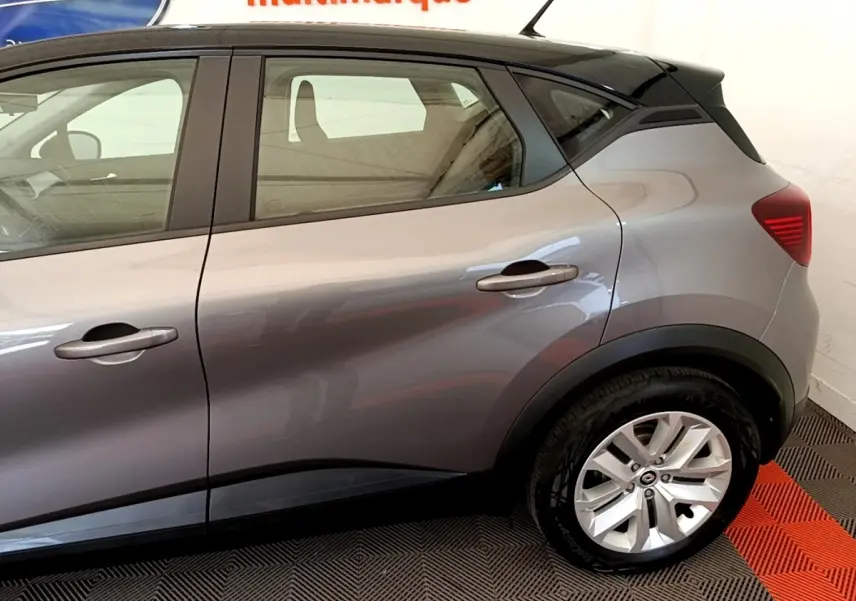 Vue latérale droite du Renault Captur Zen E-Tech hybride gris foncé, mettant en valeur la porte arrière et la roue arrière.