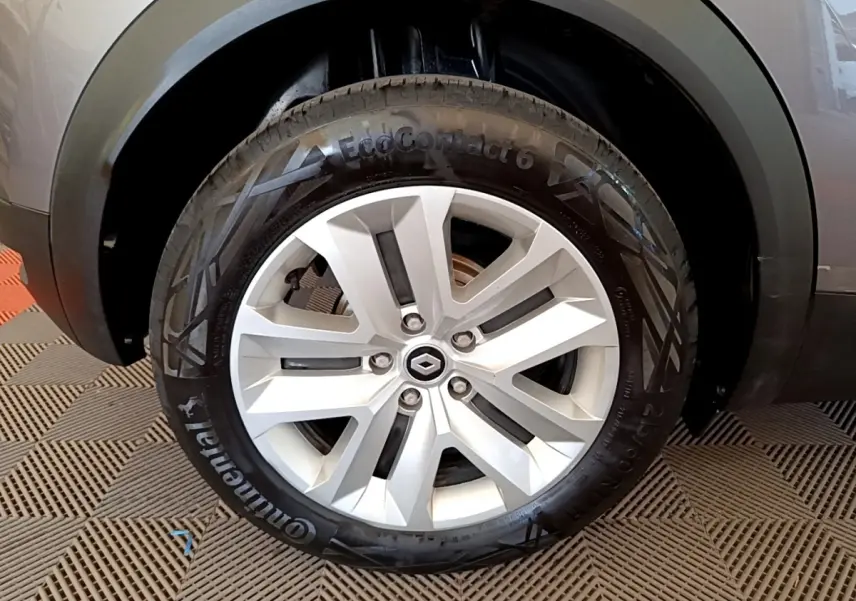 Gros plan sur la roue arrière gauche d’un Renault Captur gris foncé, mettant en valeur la jante et l’arche de roue noire.