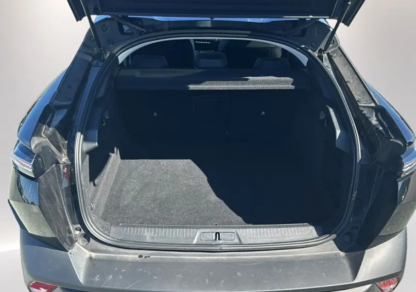 Coffre ouvert d'une Peugeot 408 Hybrid 145 allure e-dcs6 noire, vue arrière montrant l'espace de chargement vide.