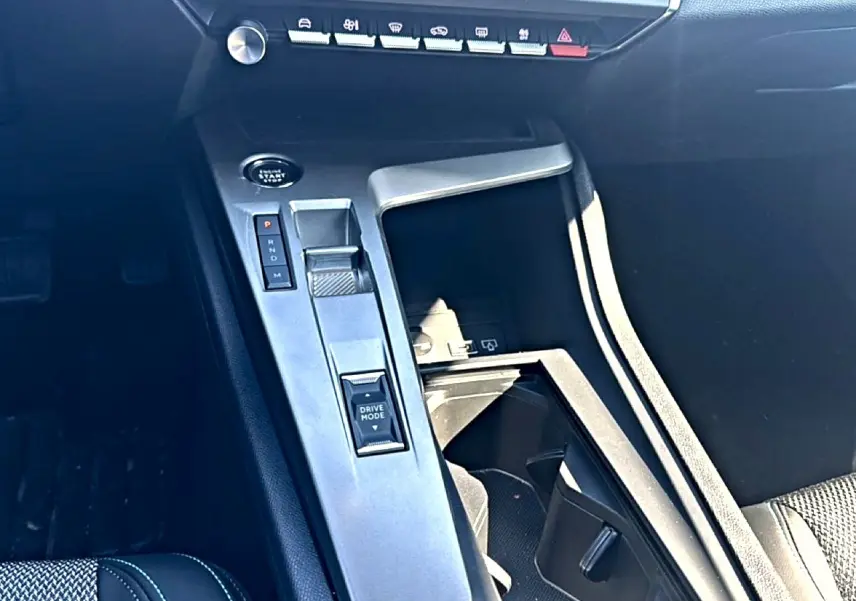 Vue rapprochée de la console centrale intérieure de la Peugeot 408 Hybrid 145 allure 2025 avec commandes de boîte auto et bouton Drive Mode.