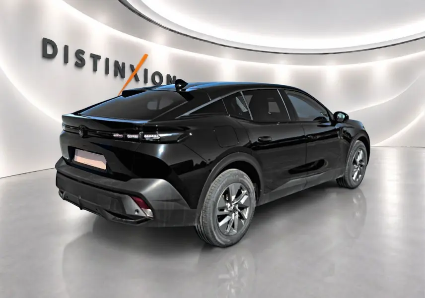 Vue 3/4 arrière droite d'une Peugeot 408 Hybrid 145 allure noire avec jantes alu et vitres teintées dans un showroom.