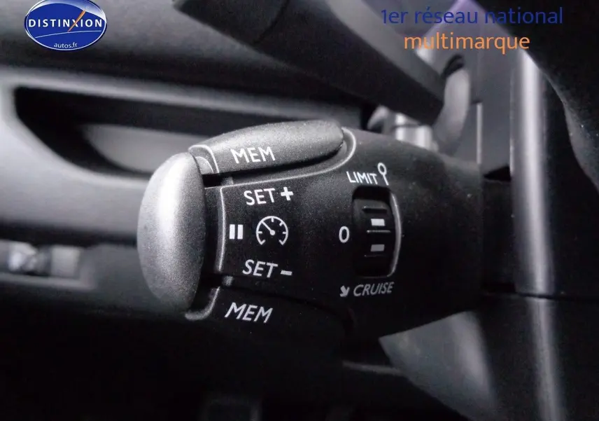 Vue intérieure côté conducteur du Peugeot Expert gris avec sièges tissu gris et noir, volant et ceintures visibles.