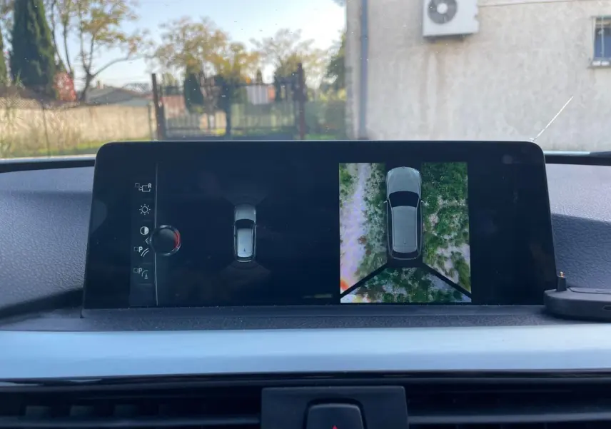 Écran de bord de BMW Série 3 Touring F31 blanc montrant la vue 360° de l'environnement extérieur en stationnement.