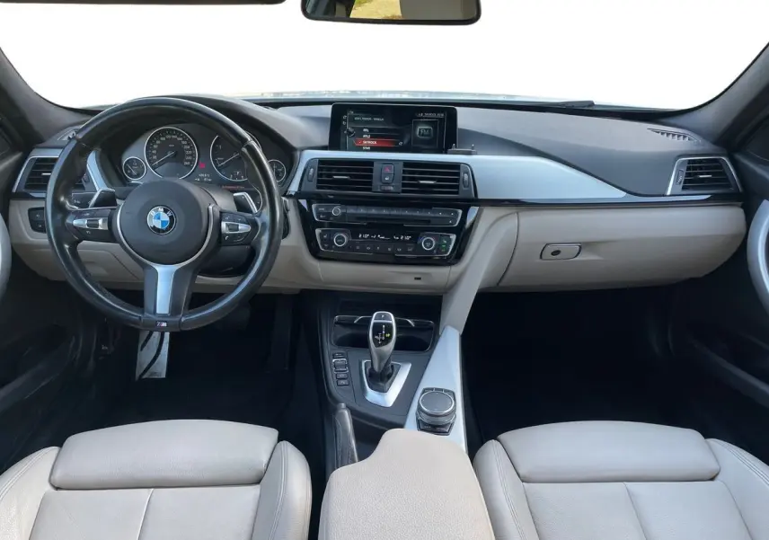 Vue intérieure avant de la BMW Série 3 Touring F31 330DA M Sport 2017 avec tableau de bord noir et sièges cuir beige.