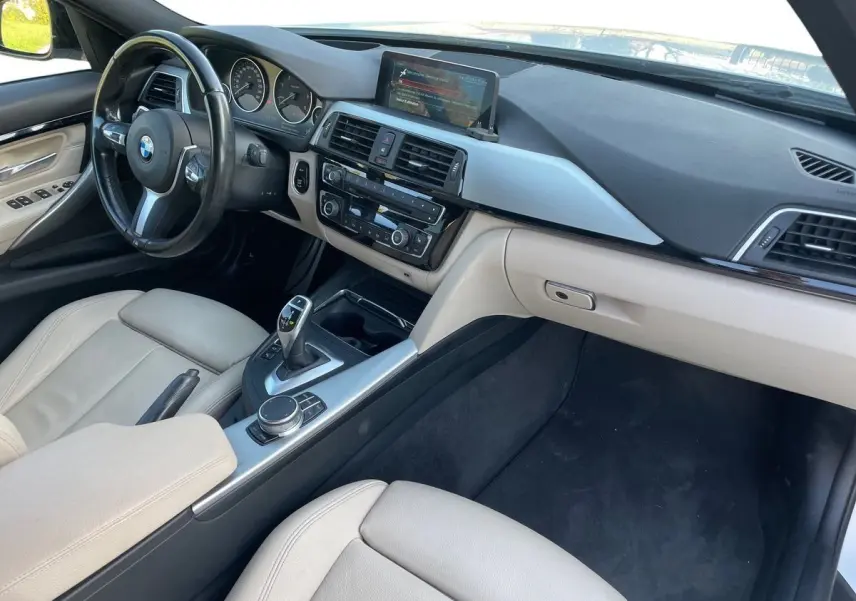 Vue intérieure côté conducteur de la BMW Série 3 Touring F31 330DA XDrive 2017 avec sellerie cuir beige et console centrale moderne.