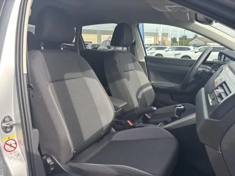 Intérieur avant du Volkswagen Taigo 2025 en tissu noir, vue côté gauche avec volant et console centrale visibles.