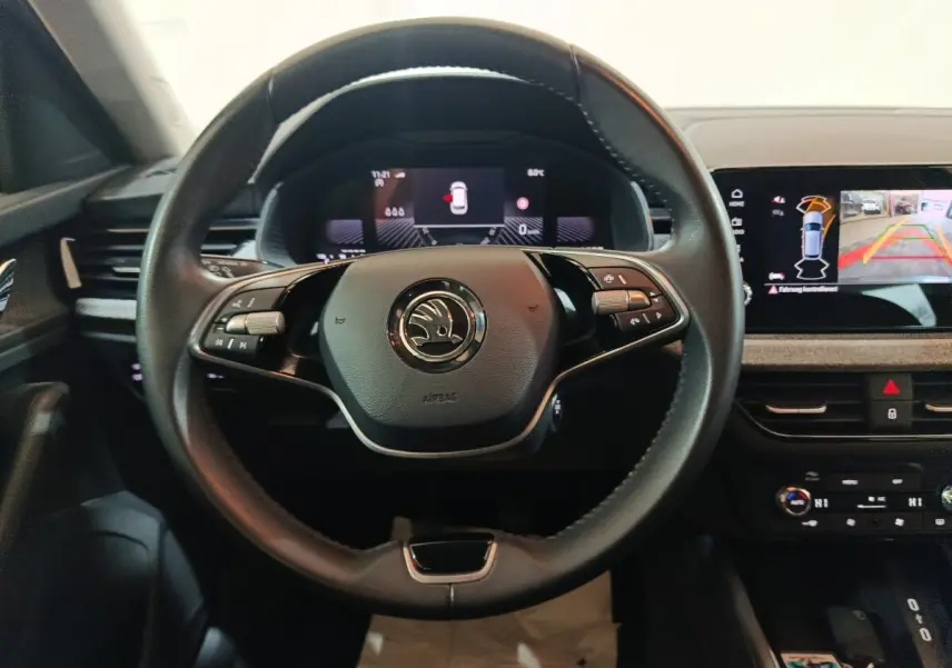 Vue frontale du volant cuir noir et du tableau de bord digital du Skoda Kamiq gris clair 2024, avec écran tactile central.