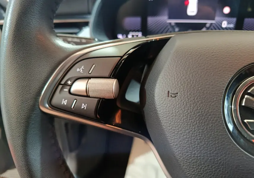 Gros plan sur le volant cuir noir du Skoda Kamiq 2024, avec commandes audio et molette métallique côté gauche.
