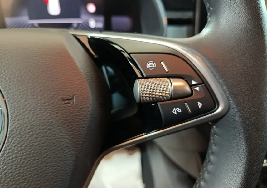 Gros plan sur les commandes droite du volant cuir noir du Skoda Kamiq gris clair 2024, avec molette et boutons multifonctions.