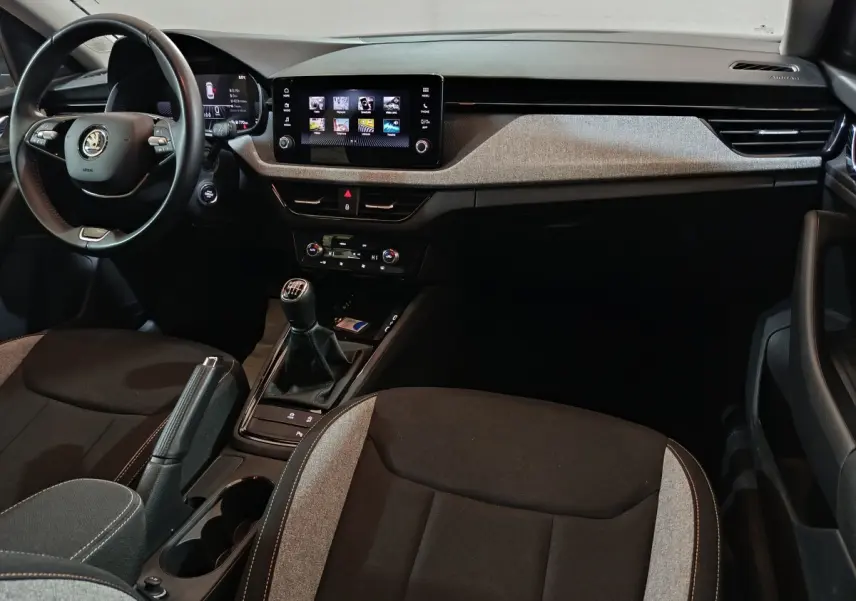 Intérieur avant du Skoda Kamiq 2024, vue côté conducteur, volant cuir, écran tactile central et levier de vitesses manuel.