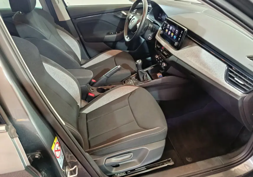 Intérieur avant droit du Skoda Kamiq gris clair 2024, sièges bi-ton, tableau de bord avec écran tactile central.