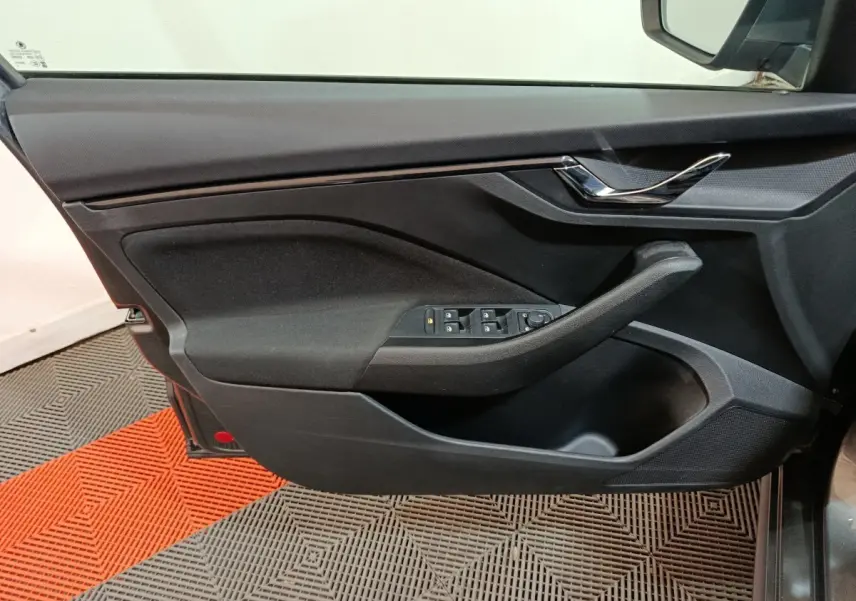 Vue rapprochée de la porte avant gauche noire du Skoda Kamiq 2024 avec commandes de vitres et poignée chromée.