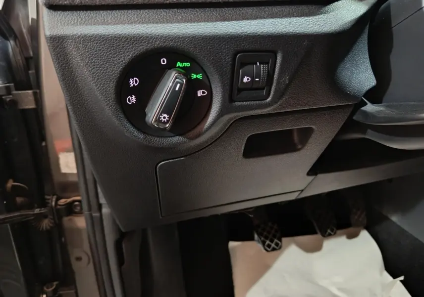Détail du panneau de commande des phares avec réglage de hauteur, côté gauche intérieur d’un Skoda Kamiq gris clair 2024.