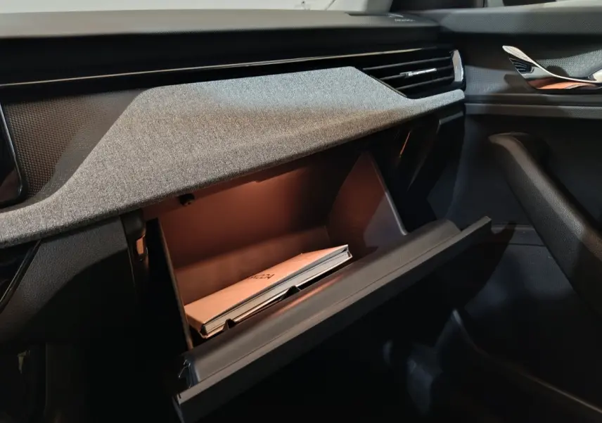 Vue intérieure côté passager du coffre à gants ouvert du Skoda Kamiq gris clair 2024 avec manuel visible.
