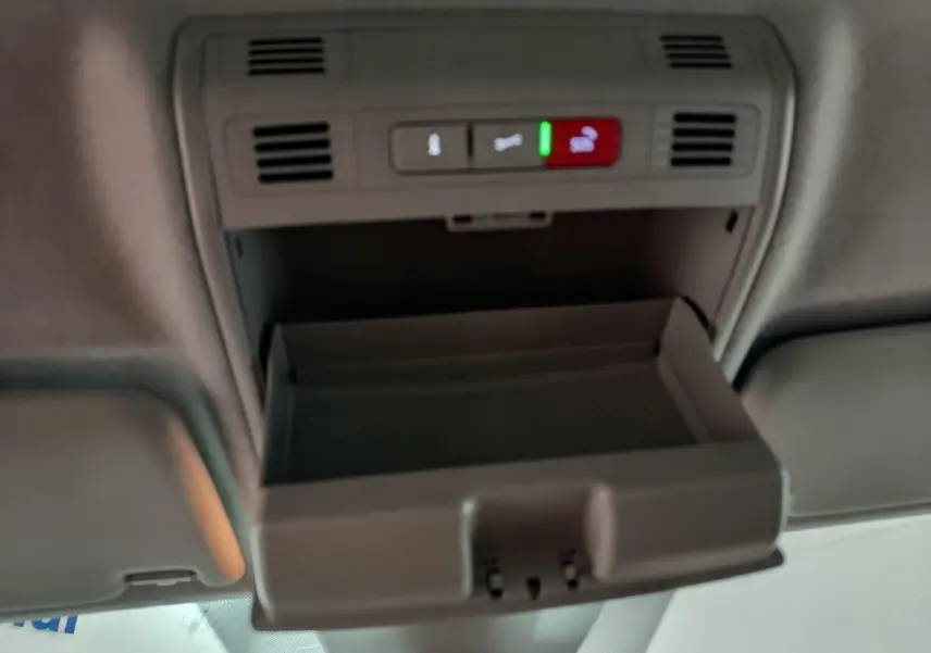 Vue intérieure en plongée du rangement plafond ouvert du Skoda Kamiq gris clair 2024 avec commandes d'urgence et ventilation.