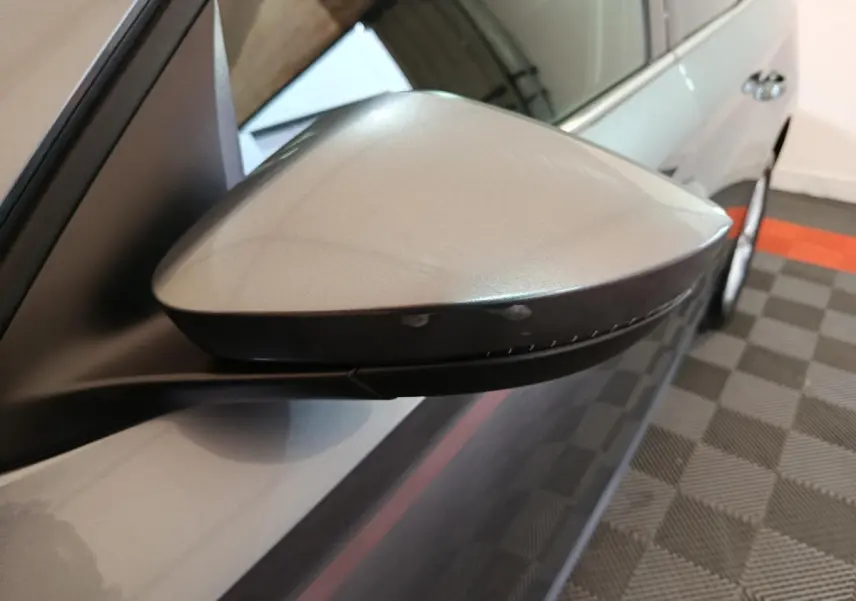 Rétroviseur côté gauche gris clair du Skoda Kamiq 2024, vue rapprochée avec carrosserie et roue arrière visibles.