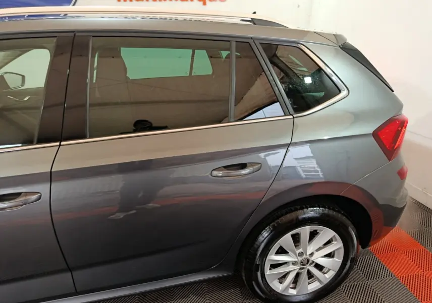 Vue latérale droite d'un Skoda Kamiq gris clair 2024, mettant en valeur la porte arrière et la roue arrière.