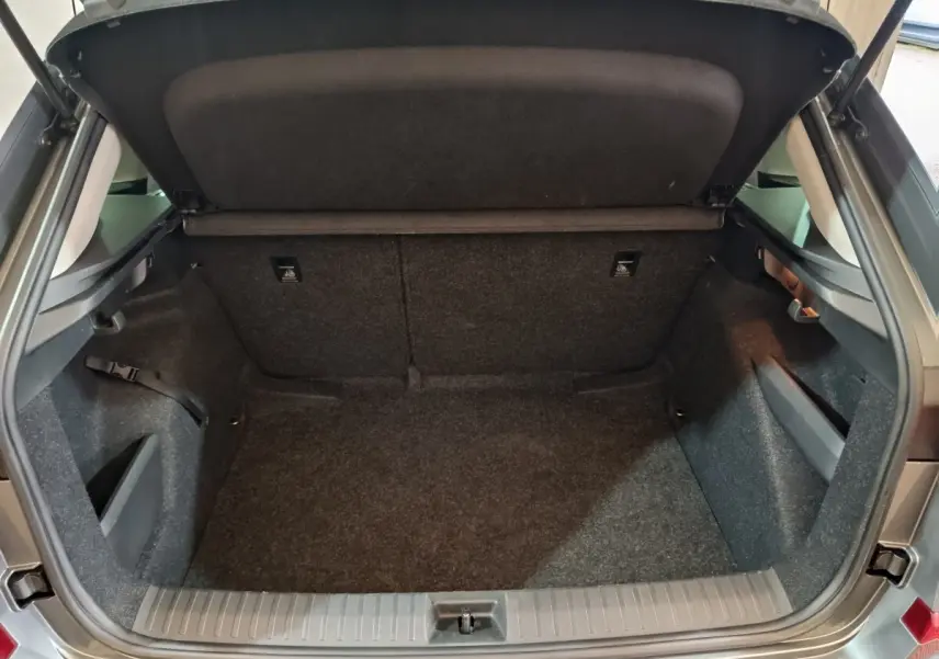 Coffre ouvert vu de l'arrière d'un Skoda Kamiq gris clair, montrant un espace de chargement vide et bien fini.