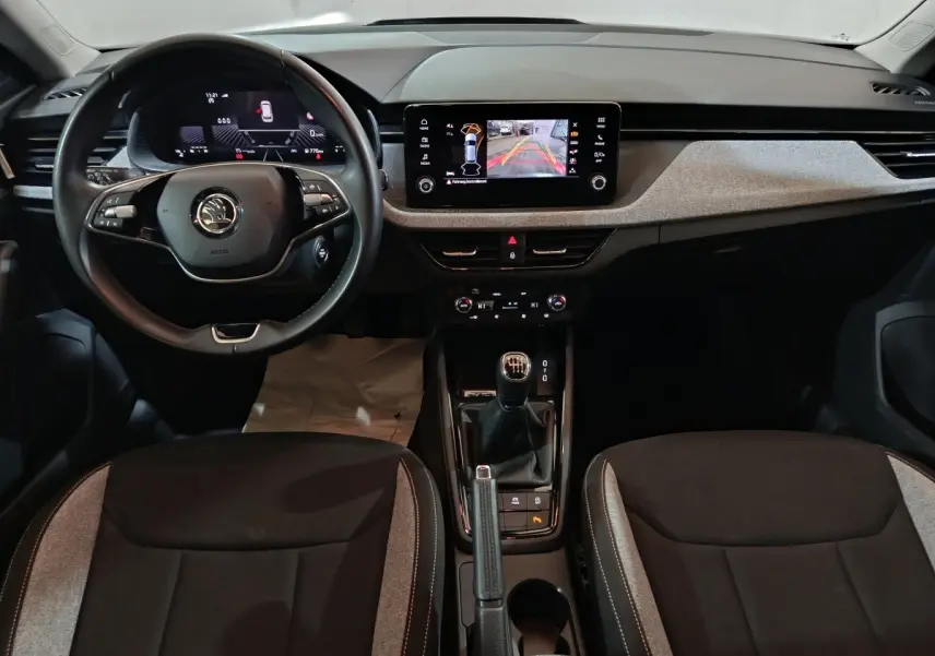Intérieur de la Skoda Kamiq 2024, vue frontale du poste de conduite avec volant cuir et écran tactile central.