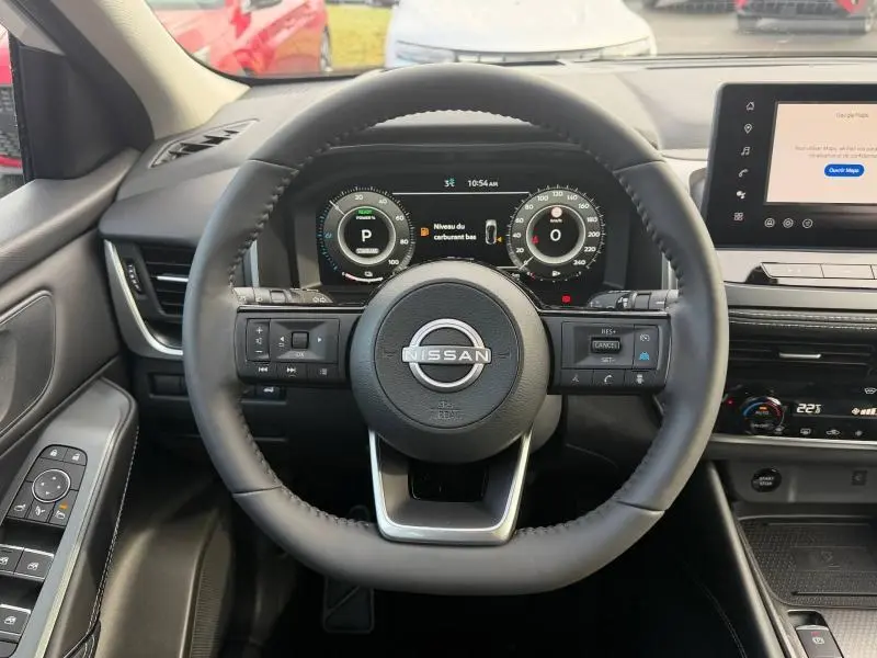 Vue intérieure centrée sur le volant du Nissan Qashqai Hybrid e-POWER 2025 avec tableau de bord numérique et écran tactile.