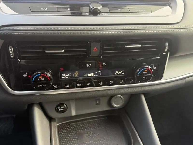 Tableau de bord du Nissan Qashqai Hybrid e-POWER 2025, vue rapprochée sur la climatisation digitale et les commandes centrales.