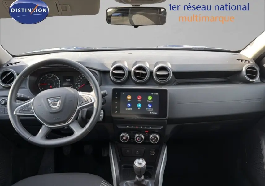 Vue frontale de l'habitacle du Dacia Duster 2022, tableau de bord noir avec écran tactile et volant multifonction.