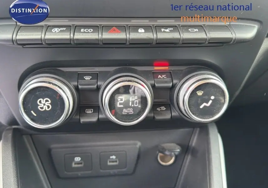 Gros plan sur la console centrale du Dacia Duster bleu Iron 2022, montrant les commandes de climatisation et les ports USB.