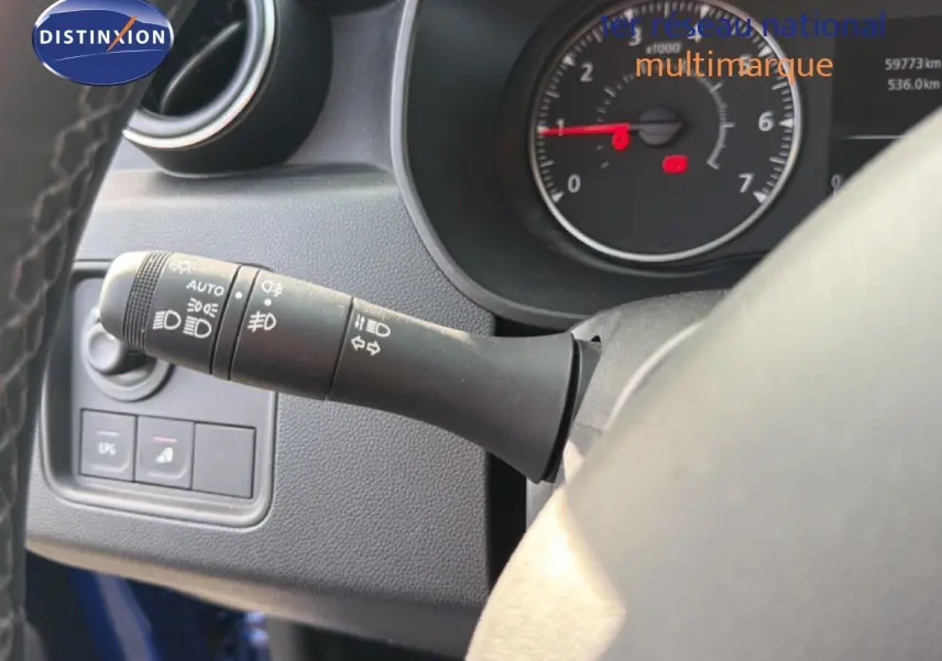 Gros plan sur la commande des phares et clignotants à gauche du volant du Dacia Duster bleu Iron 2022.
