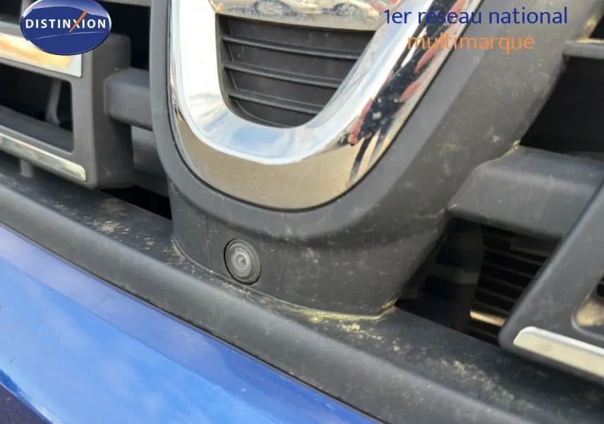 Gros plan sur la calandre avant bleu iron du Dacia Duster 2022 avec caméra de recul intégrée.