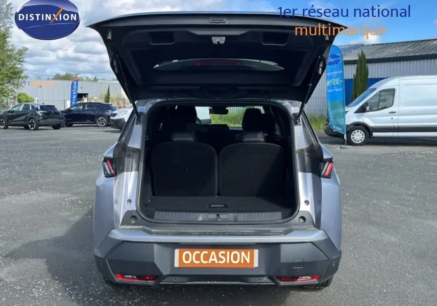 Vue arrière du Peugeot 5008 gris Artense métal 2025 avec coffre ouvert, montrant l'espace intérieur du SUV hybride.