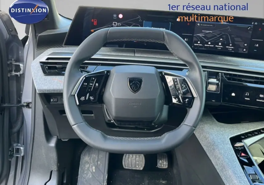 Vue intérieure centrée sur le volant multifonction gris noir du Peugeot 5008 1.2 Hybrid 145ch Allure, avec tableau de bord numérique.