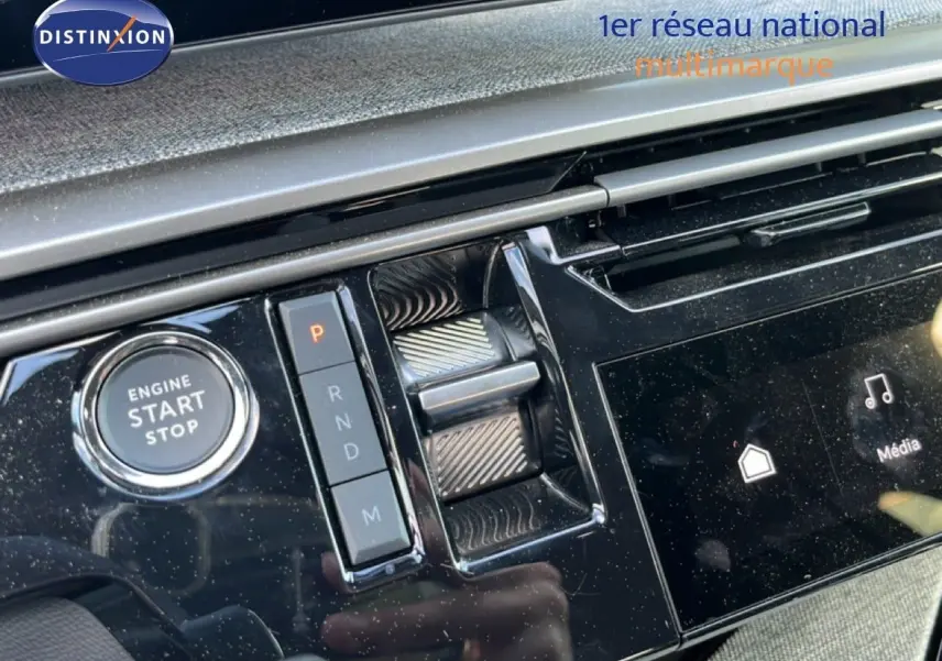 Gros plan sur la console centrale noire brillante du Peugeot 5008 gris, avec bouton start/stop et sélecteur de vitesses.
