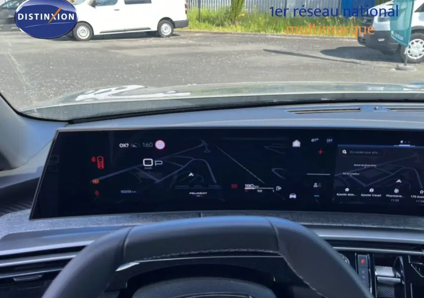 Vue intérieure du tableau de bord numérique du Peugeot 5008 gris, avec affichage de navigation et informations de conduite.