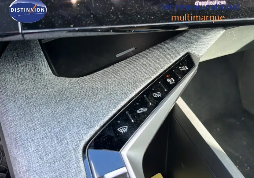 Détail de la console centrale inclinée avec commandes tactiles et finition tissu gris clair dans un Peugeot 5008 2025.
