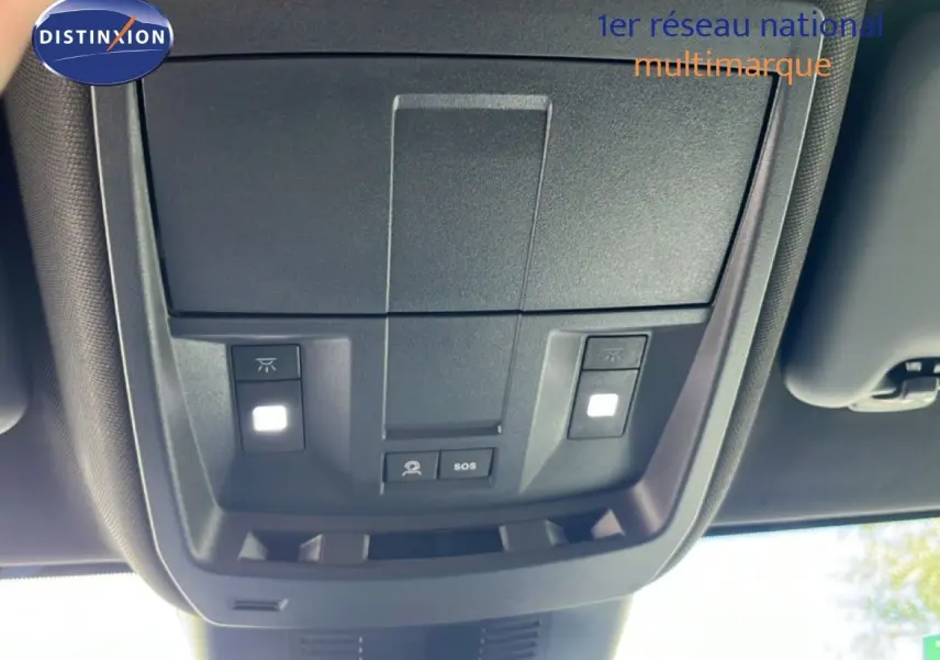 Vue en contre-plongée du plafonnier intérieur noir du Peugeot 5008 gris Artense, avec boutons d’éclairage et SOS visibles.