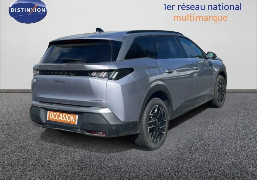 Vue 3/4 arrière droite d’un Peugeot 5008 gris Artense métallisé avec jantes noires et vitres teintées.