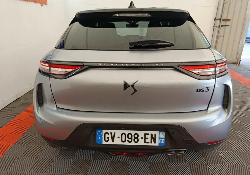 Vue arrière d'une DS3 gris foncé 2024 avec feux LED et double sortie d'échappement visible en intérieur showroom.
