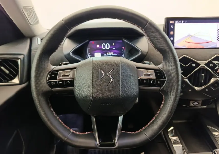 Vue rapprochée du volant cuir DS avec commandes multifonctions et tableau de bord numérique du DS3 2024.