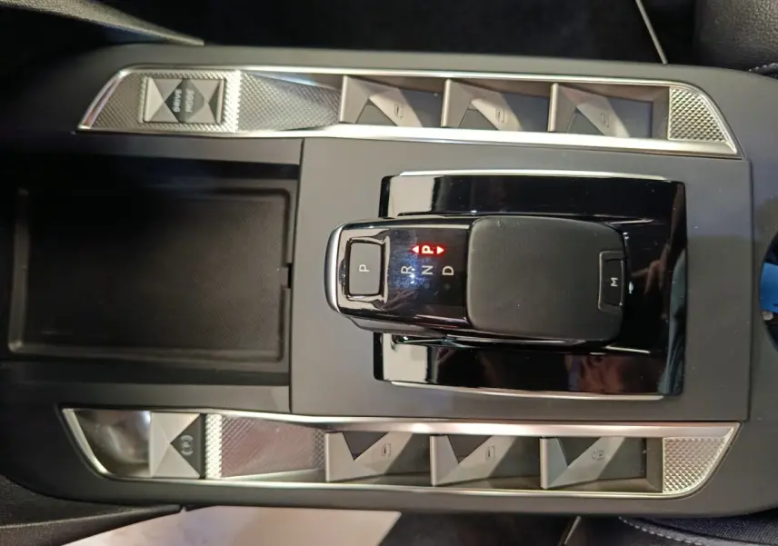 Vue plongeante sur la console centrale noire de la DS3 2024 avec levier de boîte auto et boutons argentés.