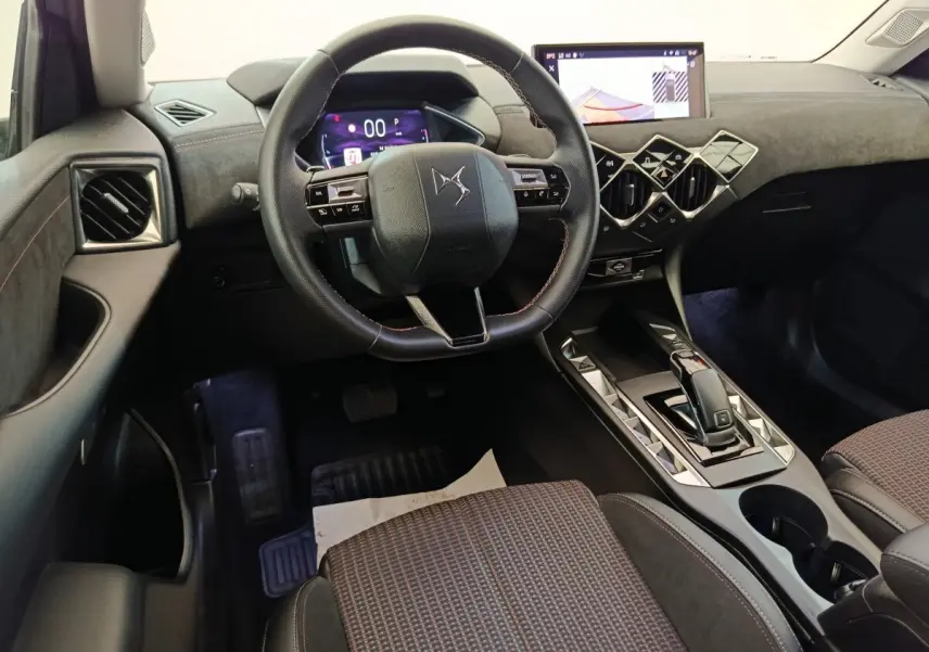 Vue intérieure côté conducteur du DS3 2024 gris foncé, volant cuir, écran tactile et console centrale design géométrique.