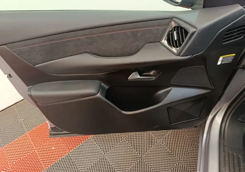 Vue intérieure côté gauche de la porte avant gris foncé du DS3 2024 avec garniture noire et surpiqûres rouges.