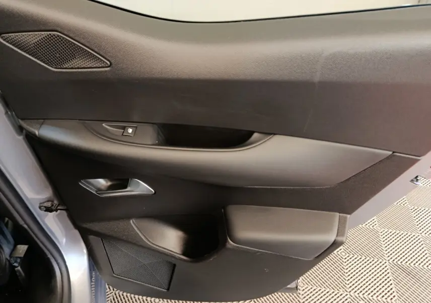 Vue rapprochée de la porte arrière gauche gris foncé du DS3 2024 avec poignée intérieure et commande de vitre.